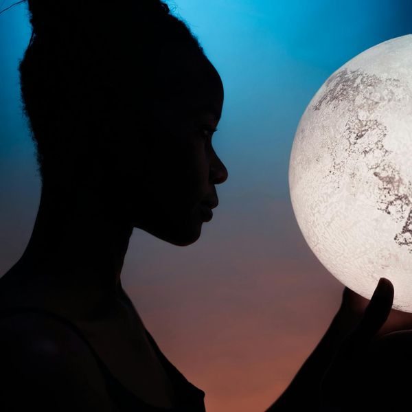 Silhouette of a woman meditating against a serene, dark background.